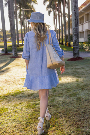 Woman wearing UPF 50+ blue button down mini dress with sun protection walking at the country club