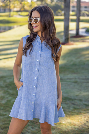 Woman wearing a UPF 50+ blue dress with sun protection standing outdoors with greenery in a country club background
