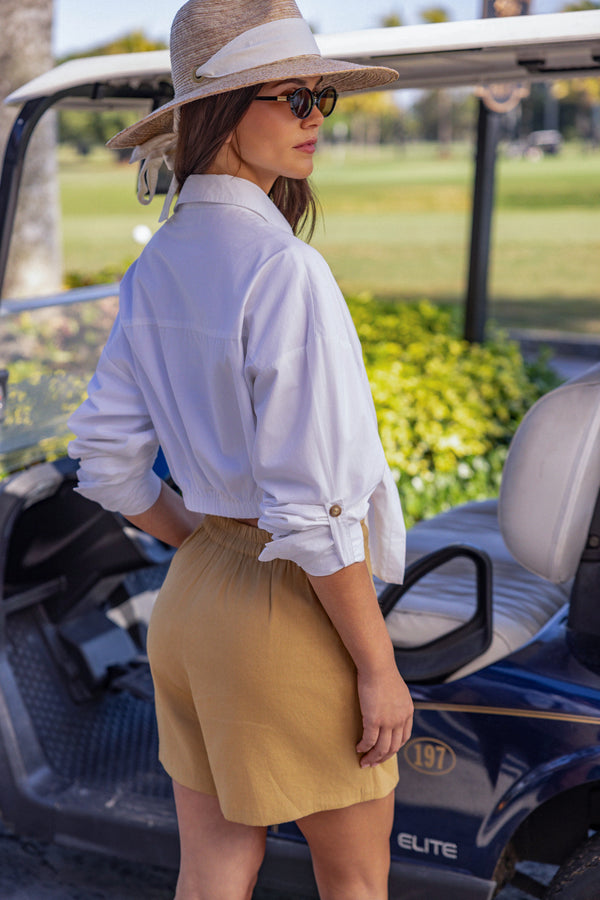 Woman wearing Crisp white UPF 50+ top with sun protection standing in front of a golf cart