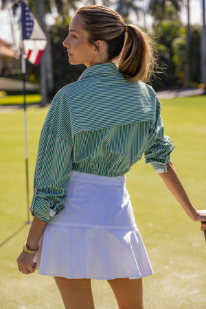 Woman wearing a UPF 50+ green stripe  shirt with sun protection on the golf course