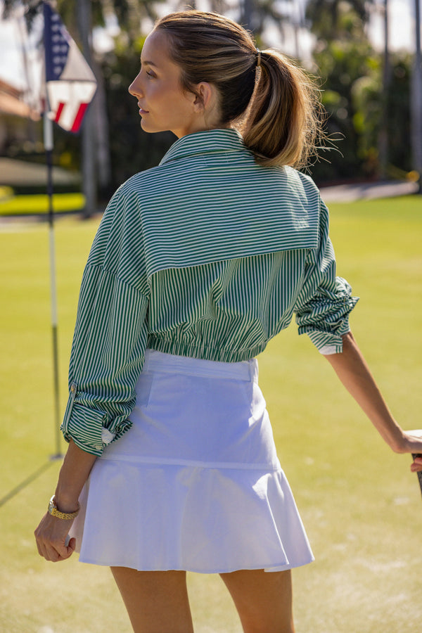Woman wearing a UPF 50+ green stripe  shirt with sun protection on the golf course