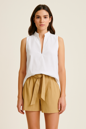 Woman wearing beige UPF 50+ shorts and sleeveless white top with sun protection on a white background
