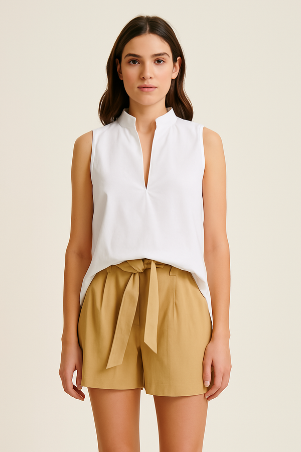 Woman wearing beige UPF 50+ shorts and sleeveless white top with sun protection on a white background